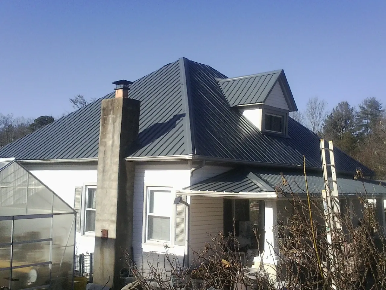 Dark blue standing seam metal roof on a white farmhouse with dormer — Slate & Tile Roof Repair by Roofing Brothers in King City
