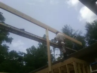 Carpenter setting a ridge beam over a new addition frame — Ice Dam Removal by Roofing Brothers in King City