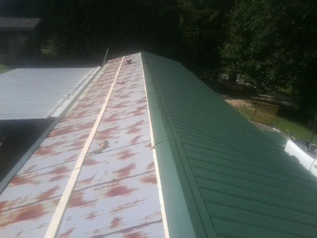 Old rusted panels beside newly installed green metal roofing — Wind Damage Roof Repair by Roofing Brothers in King City