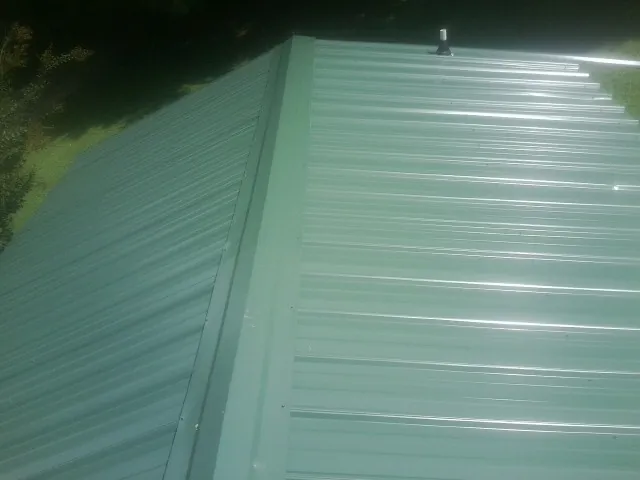 New green metal panels meeting at the ridge of a roof — Flat Roof Repair work by our crew in King City