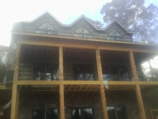 Dormers and porch framing on a large log home under construction — Roof Coating work by our crew in King City