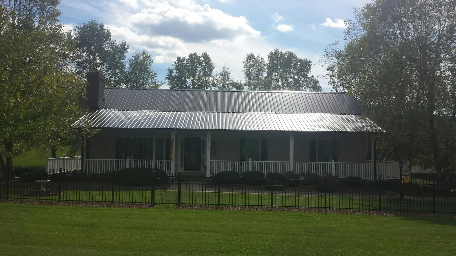Gray metal roof on a brick ranch with a full width front porch — Gutter Guard Installation work by our crew in King City
