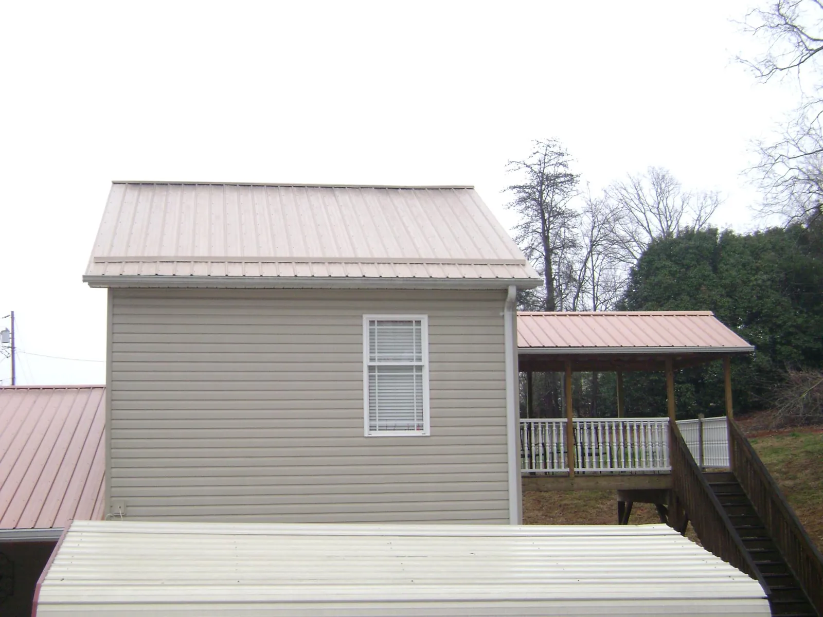 Tan metal roofs on a two story addition and attached porch, from a Roof Replacement job in King City