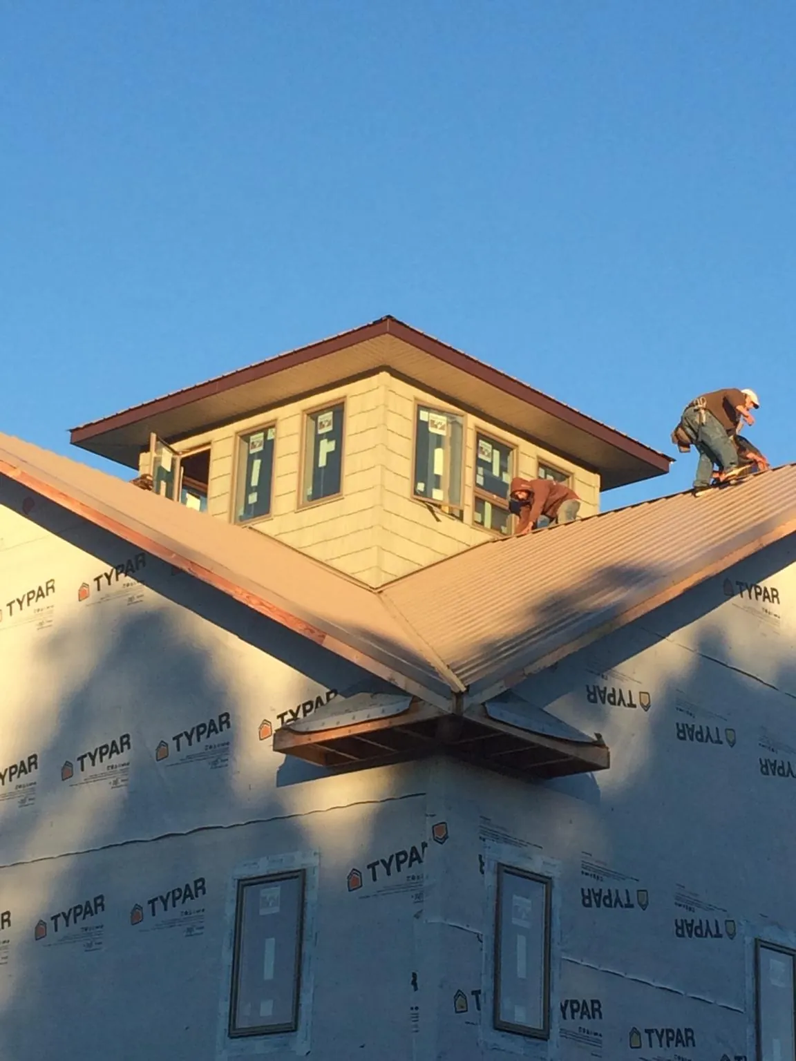Roofers working around a rooftop cupola on a new metal roof at sunset — Roof Waterproofing in King City by Roofing Brothers